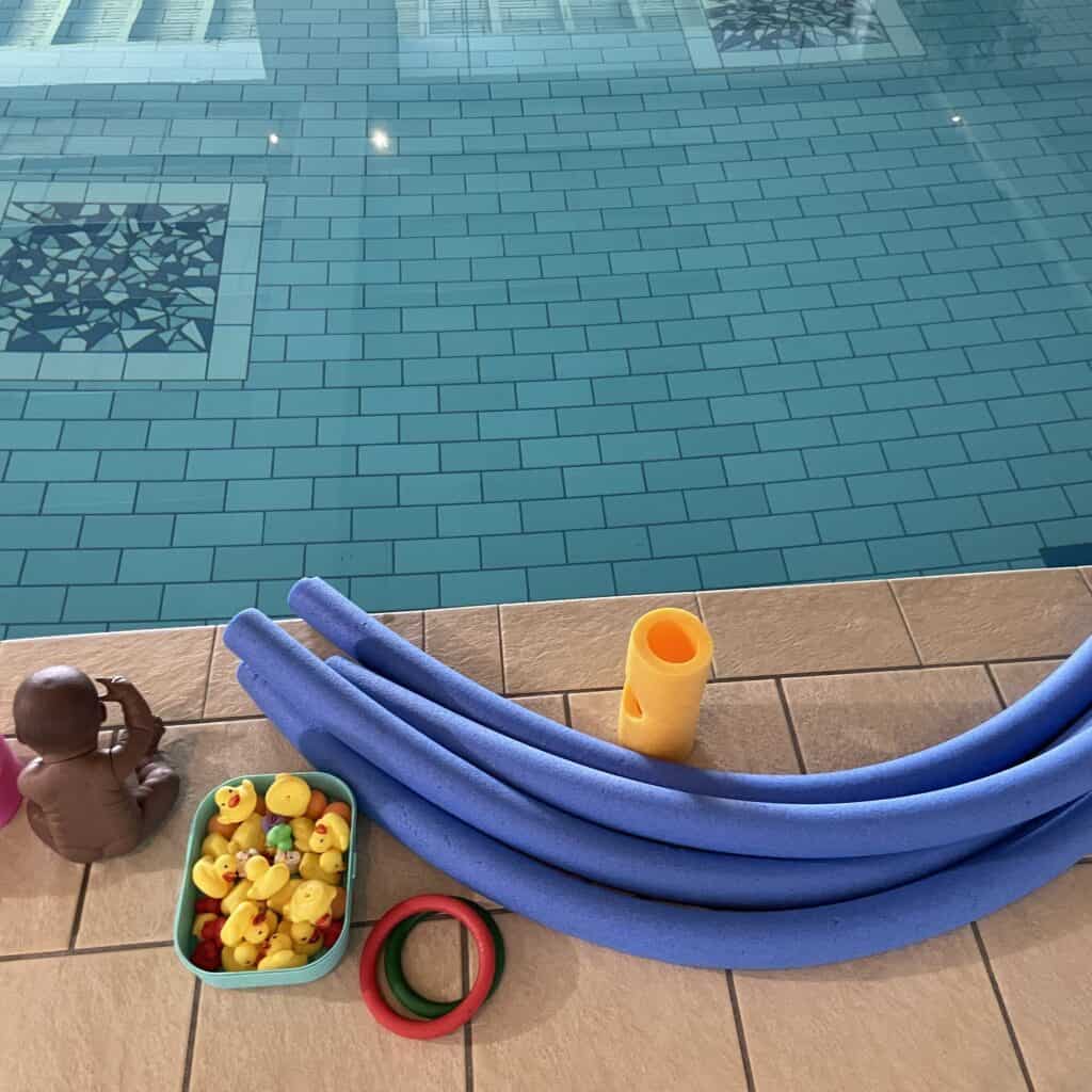 Kinderpool mit Spielzeug, Schwimmreifen und Wasserspielzeug am Beckenrand.