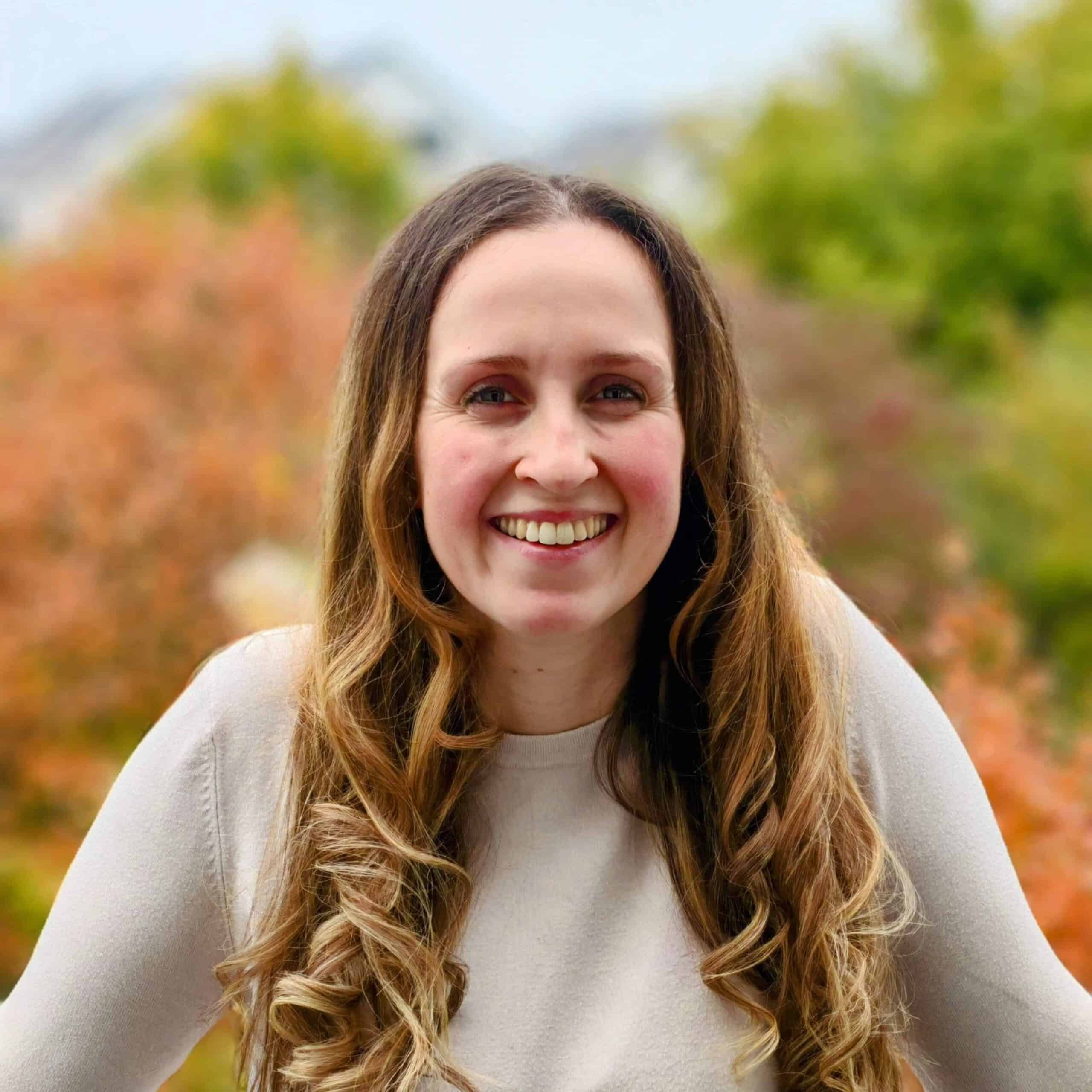 Lächelnde Hebamme im Familienbetrieb vor herbstlicher Natur.