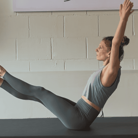 Frau macht Pilates-Übung auf Yogamatte in Studio.